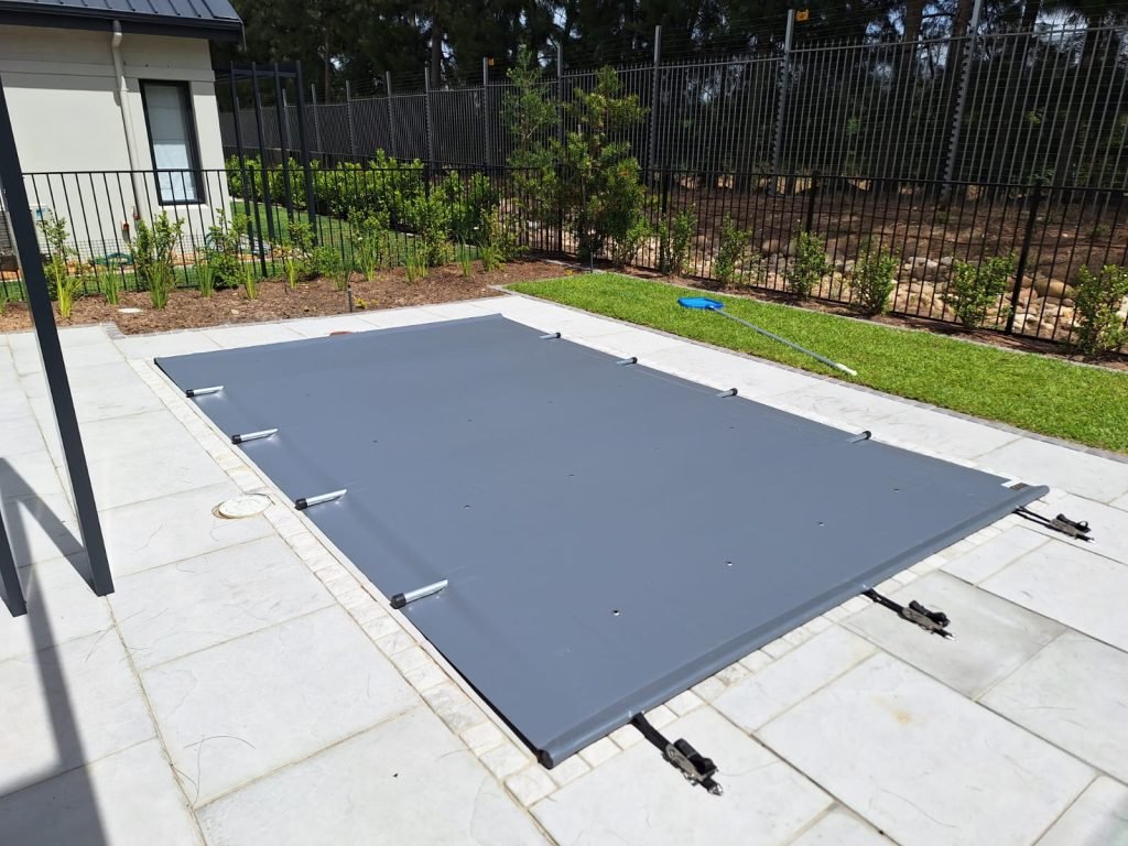 A grey pool cover in a backyard.