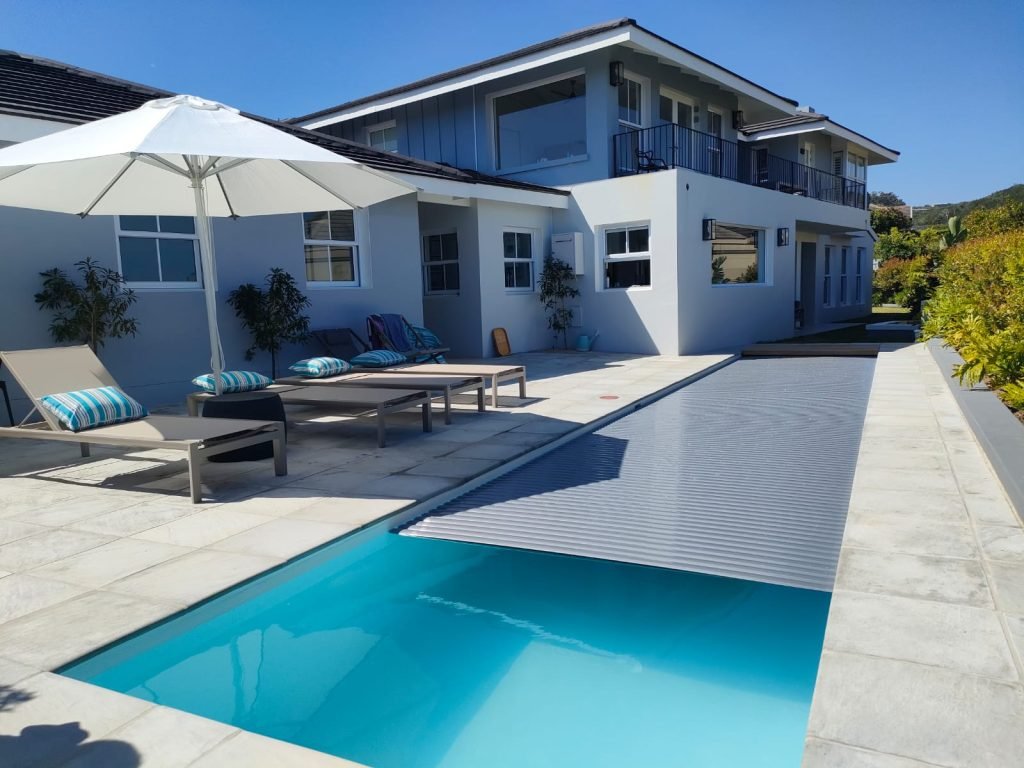 A swimming pool with an umbrella and lounge chairs.